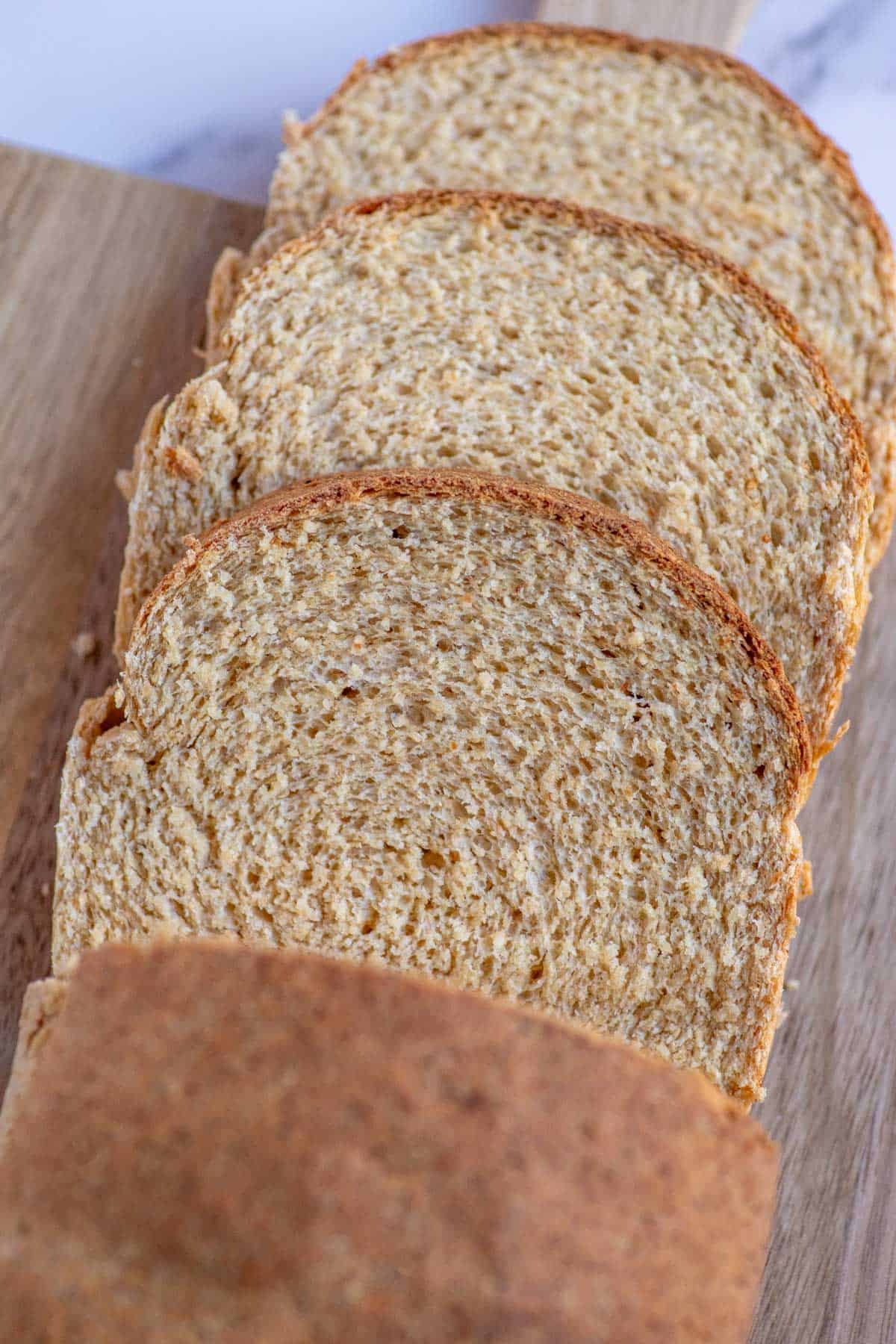 Three slices of freshly milled sandwich bread cut from a loaf on a cutting board.