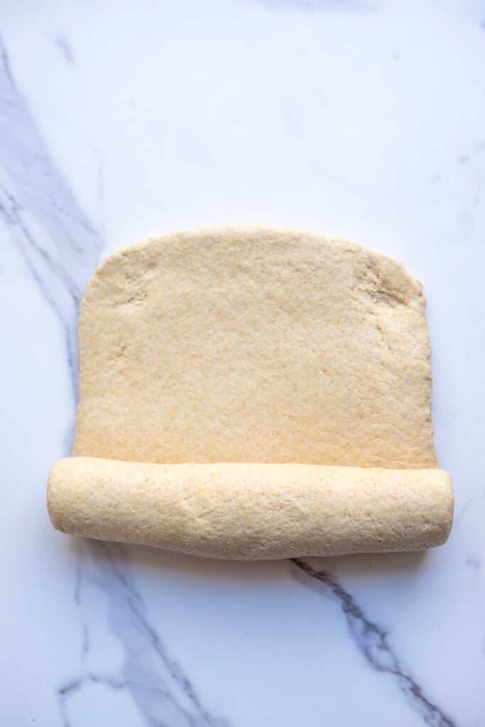 Dough in a rectangle half way rolled up.