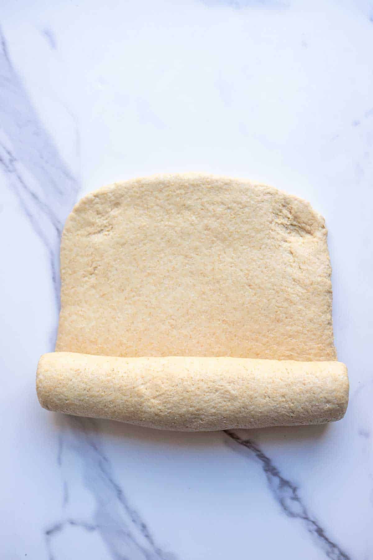 Dough in a rectangle half way rolled up.