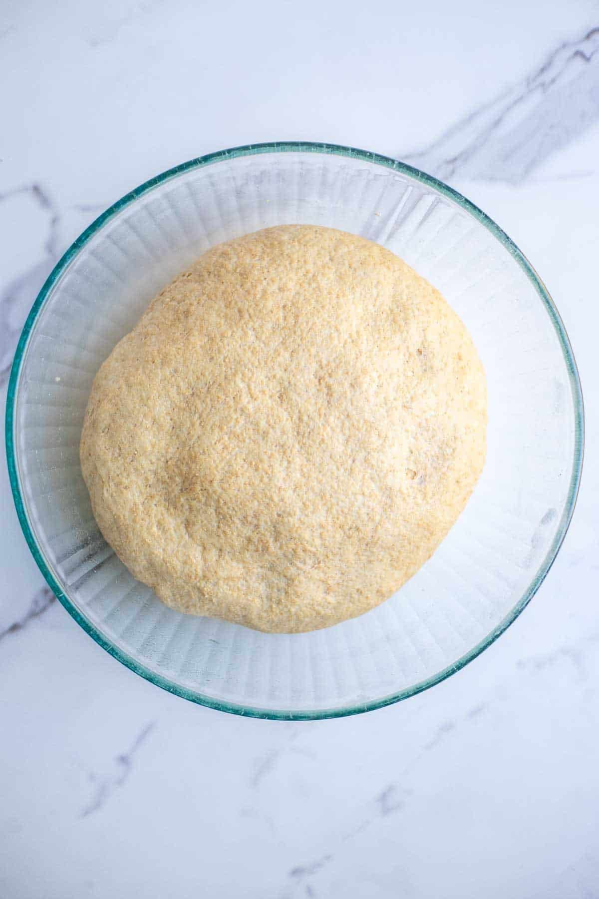 A dough ball in a glass bowl.