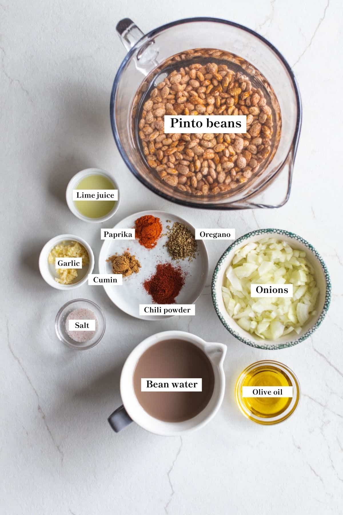 Ingredients for refried beans in bowls on a counter top.