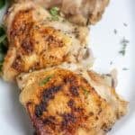 Four chicken thighs on a white platter.