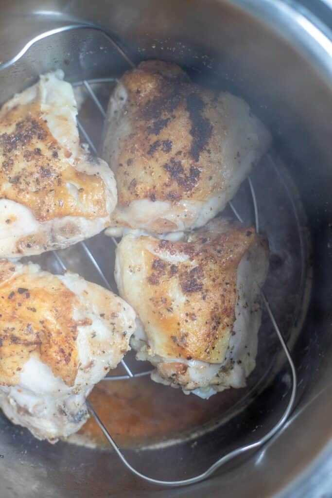 Four chicken thighs on a trivet in the Instant Pot.