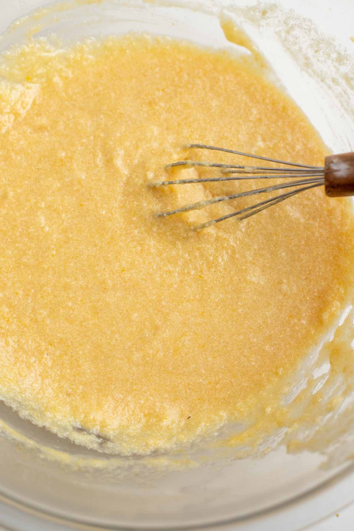 Bowl with wet ingredients in it and a whisk.