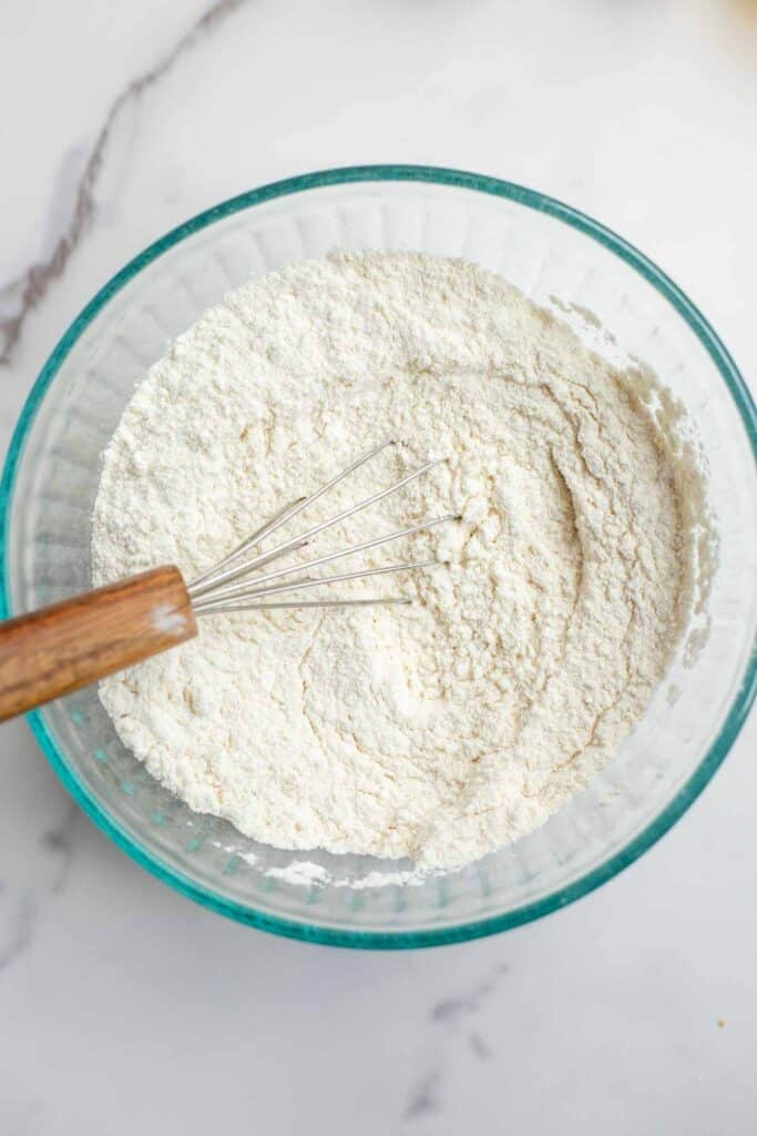 Dry ingredients in a bowl with a small whisk.
