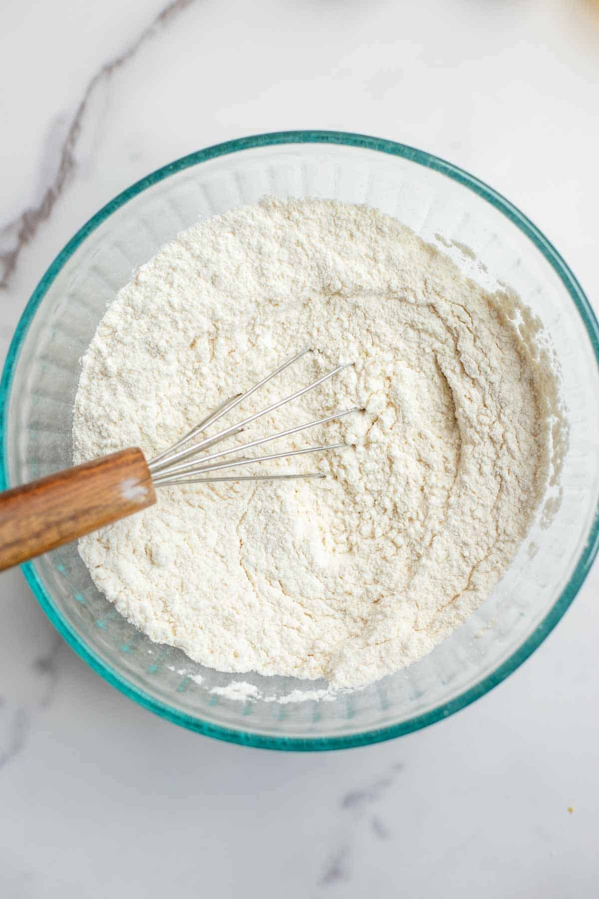 Dry ingredients in a bowl with a small whisk.