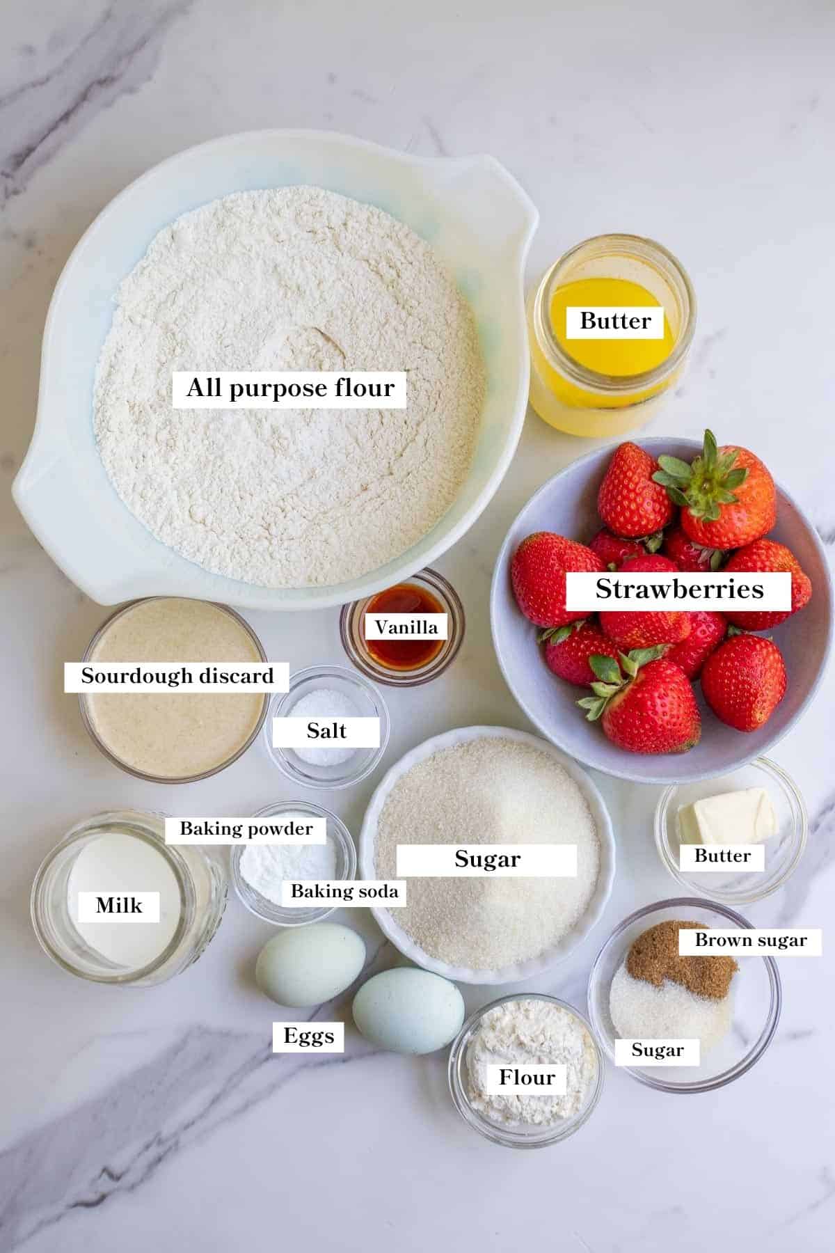 Ingredients for sourdough strawberry muffins on a marble countertop.