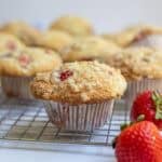 sourdough strawberry muffins and fresh strawberries on a cooling wrack.