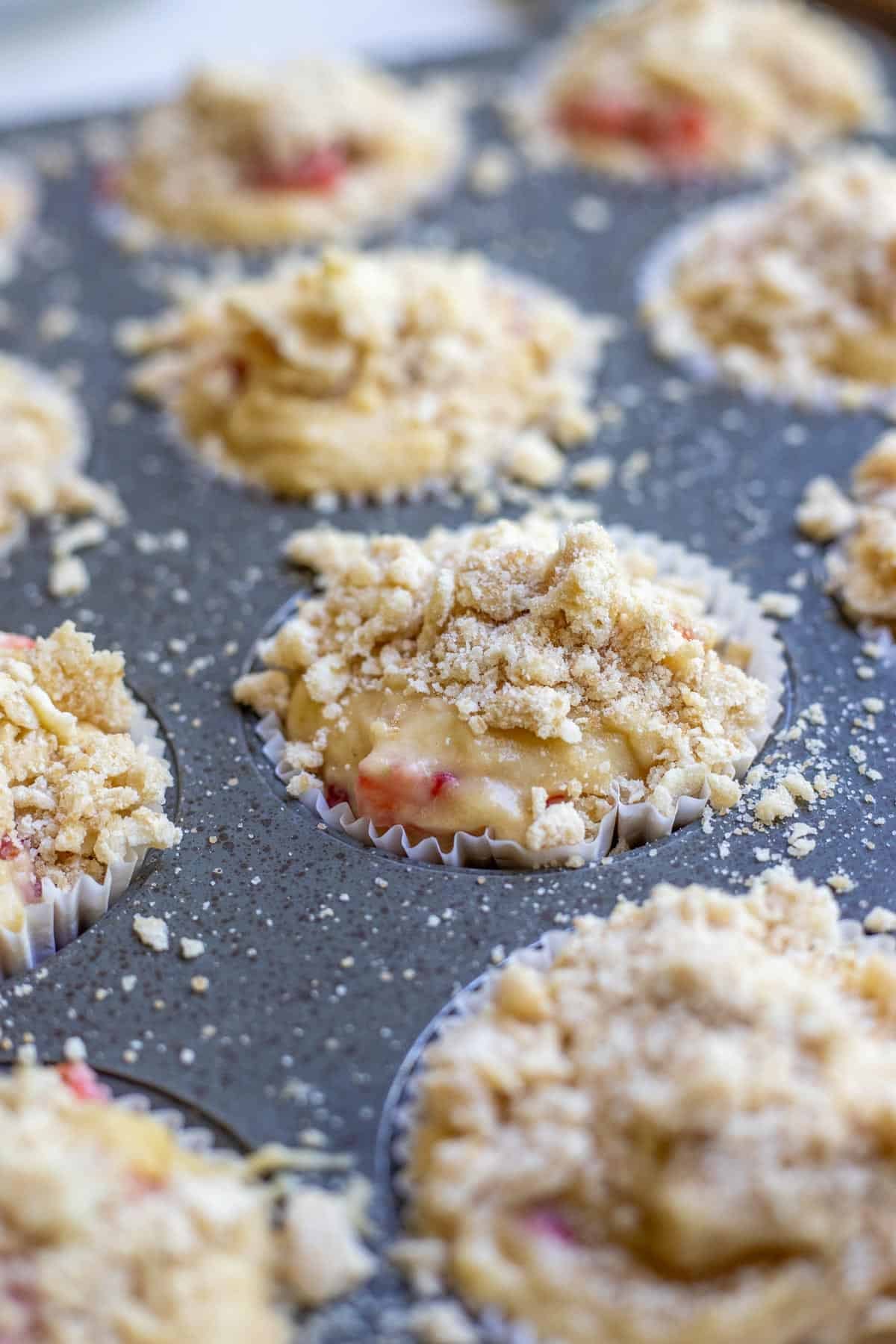 Crumble topping added to the tops of strawberry muffin batter.