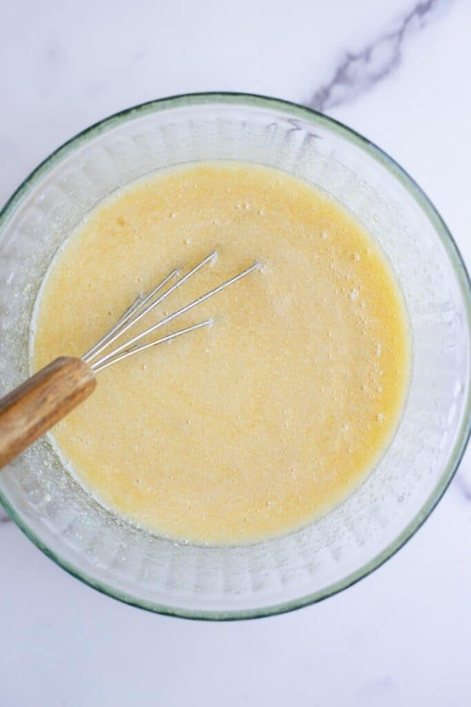 Sugar, butter, eggs, vanilla, milk, and sourdough discard mixed together in a glass bowl.