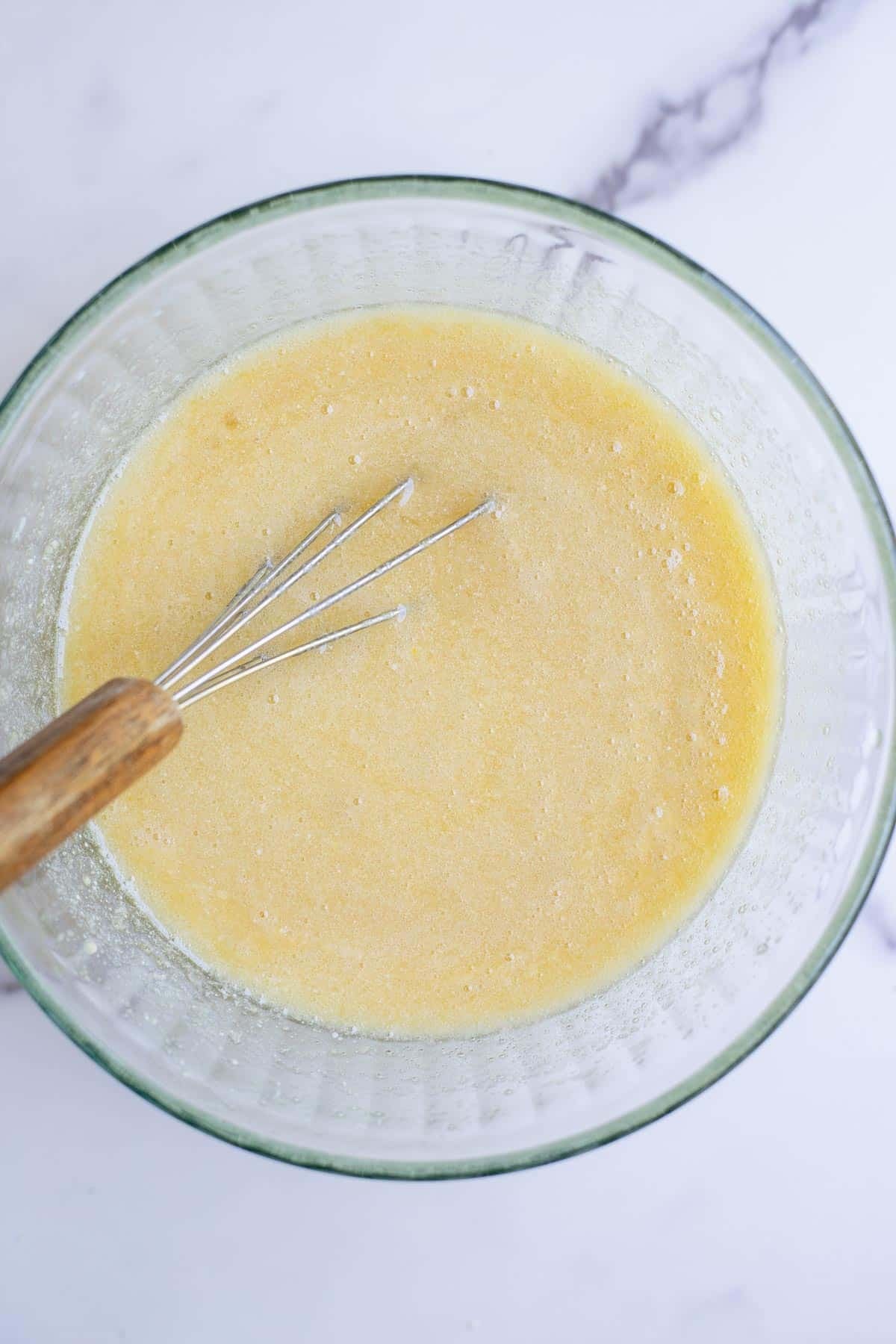 Sugar, butter, eggs, vanilla, milk, and sourdough discard mixed together in a glass bowl.