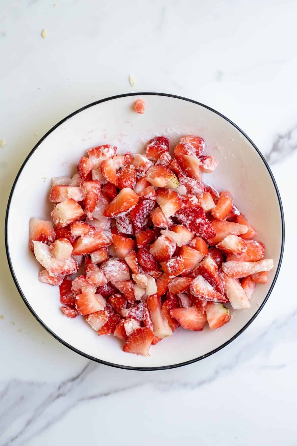 Chopped strawberries coated in flour in a white bowl.