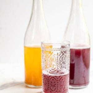 two bottles of water kefir with a glass poured in front of the bottles.