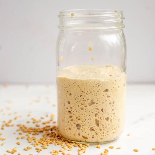 a jar of sourdough starter on a marble counter top.