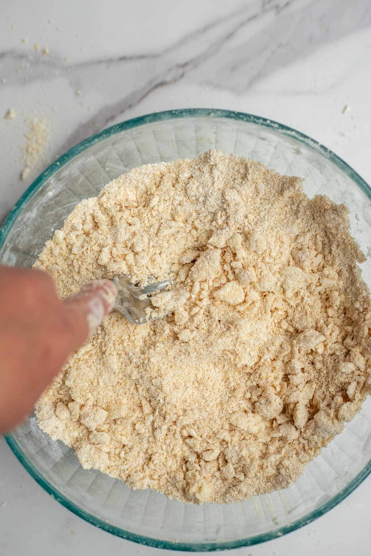 Butter added in to a bowl of dry ingredients with a fork.