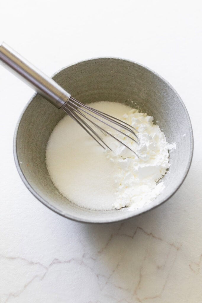 Whipped cream in a bowl with a whisk.