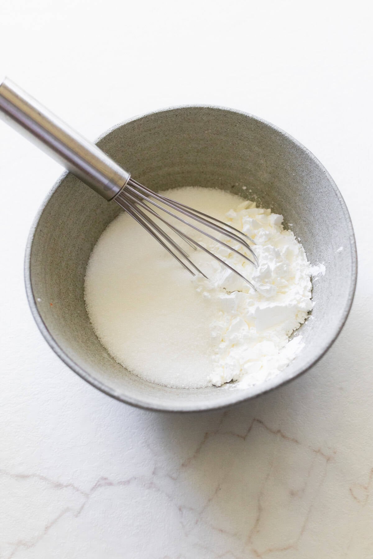 Whipped cream in a bowl with a whisk.