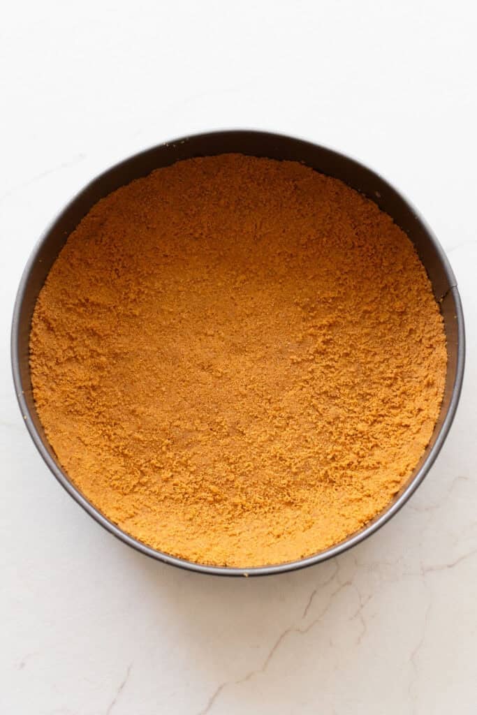 A springform pan with a graham cracker crust pressed into the bottom.