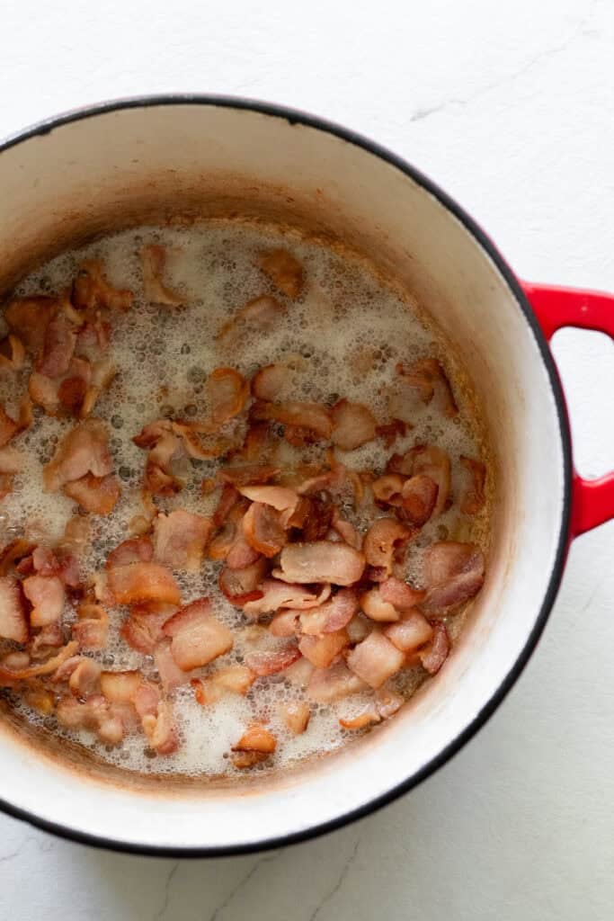 Bacon cooking in a Dutch oven.