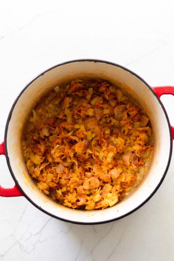 Onion and carrot added to a Dutch oven of bacon.