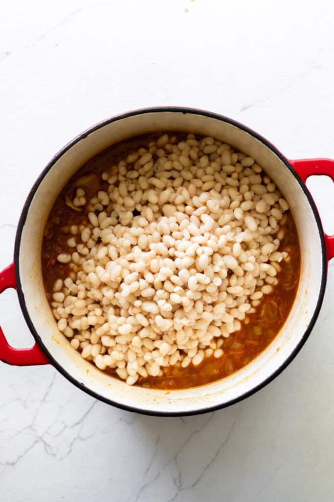 Stock and beans added to a Dutch oven.