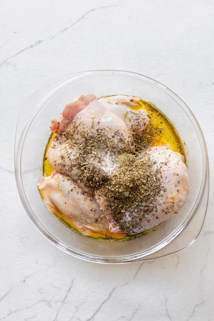 Chicken thighs in a bowl in a marinade.