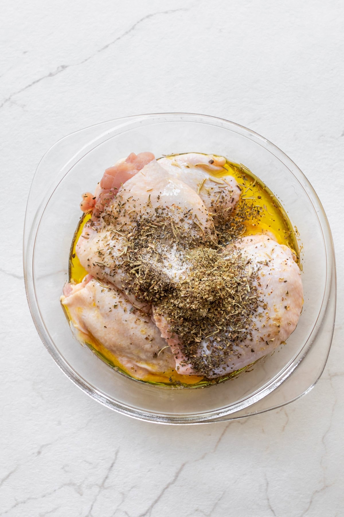 Chicken thighs in a bowl in a marinade.