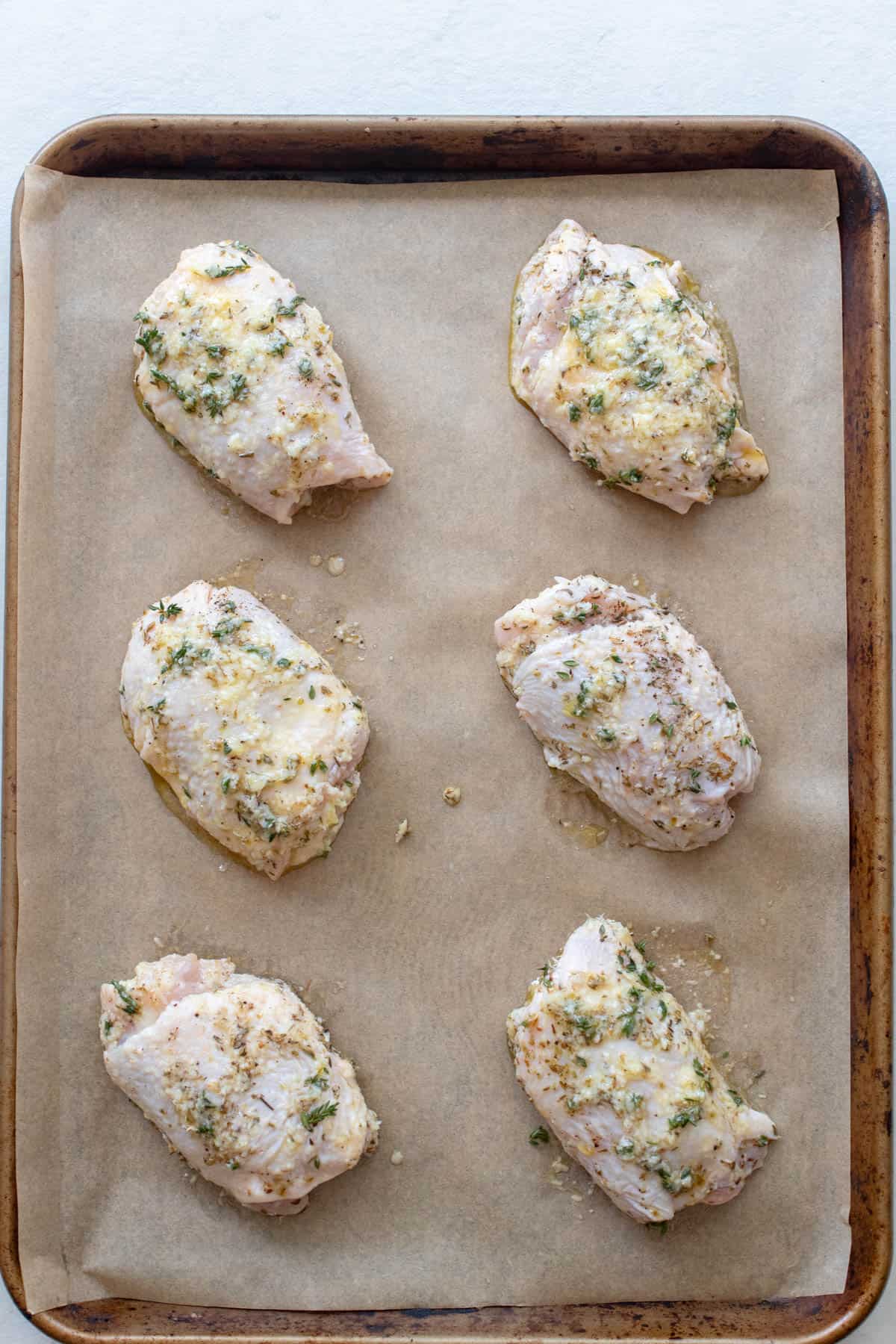 Chicken thighs on a sheet pan lined with parchment paper.