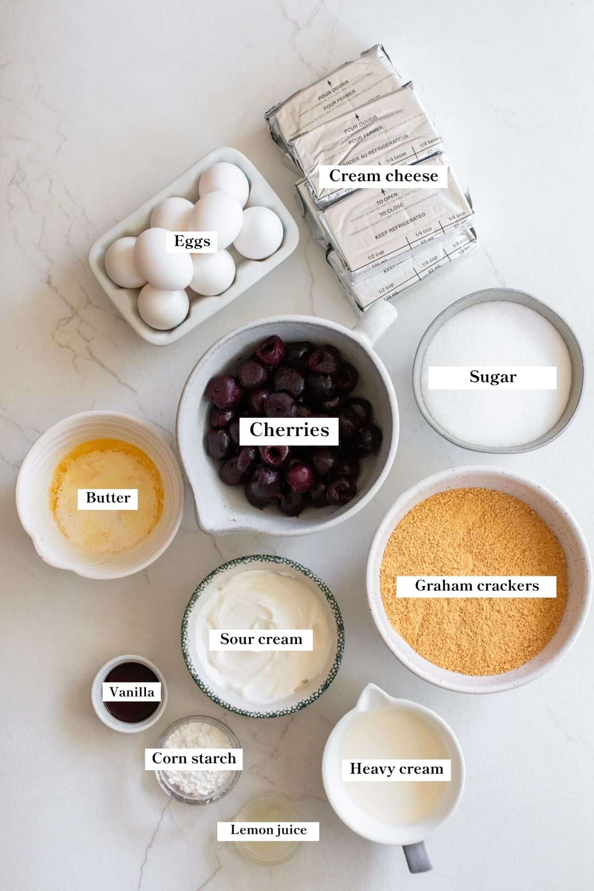 Ingredients for cherry cheesecake in bowls on a counter top.
