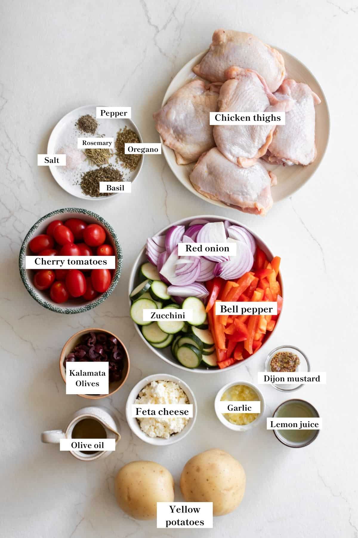 Ingredients for sheetpan Mediterranean chick and vegetables on plates on a counter top.