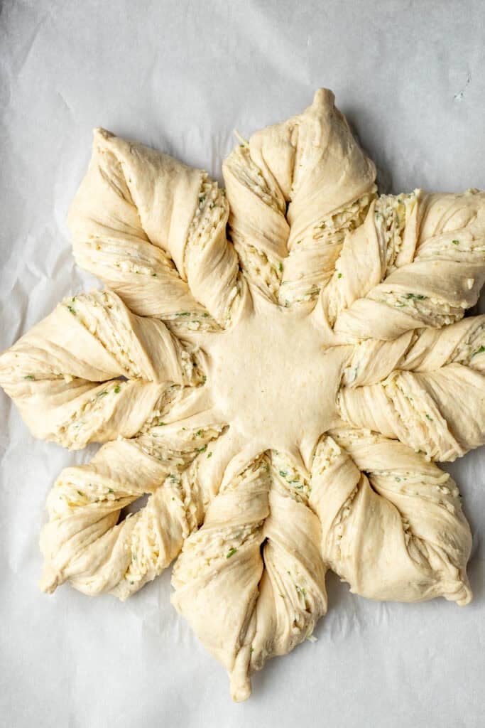 Twisting the cut sections of the sourdough cheese bread to turn them into a star shape.