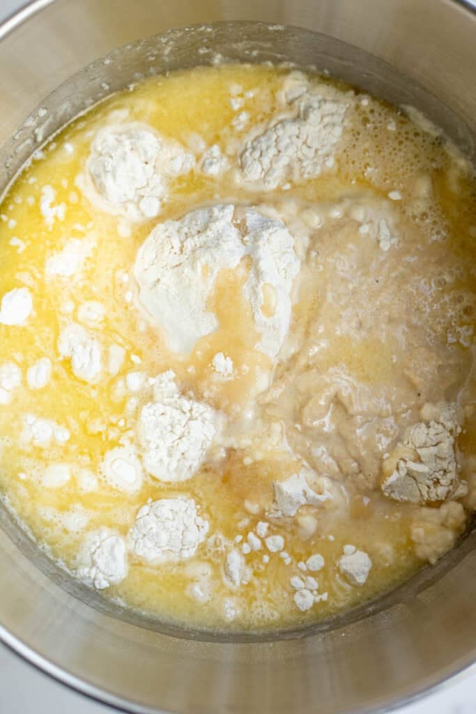 Flour, butter, water, and sourdough starter in a stainless steel mixing bowl.