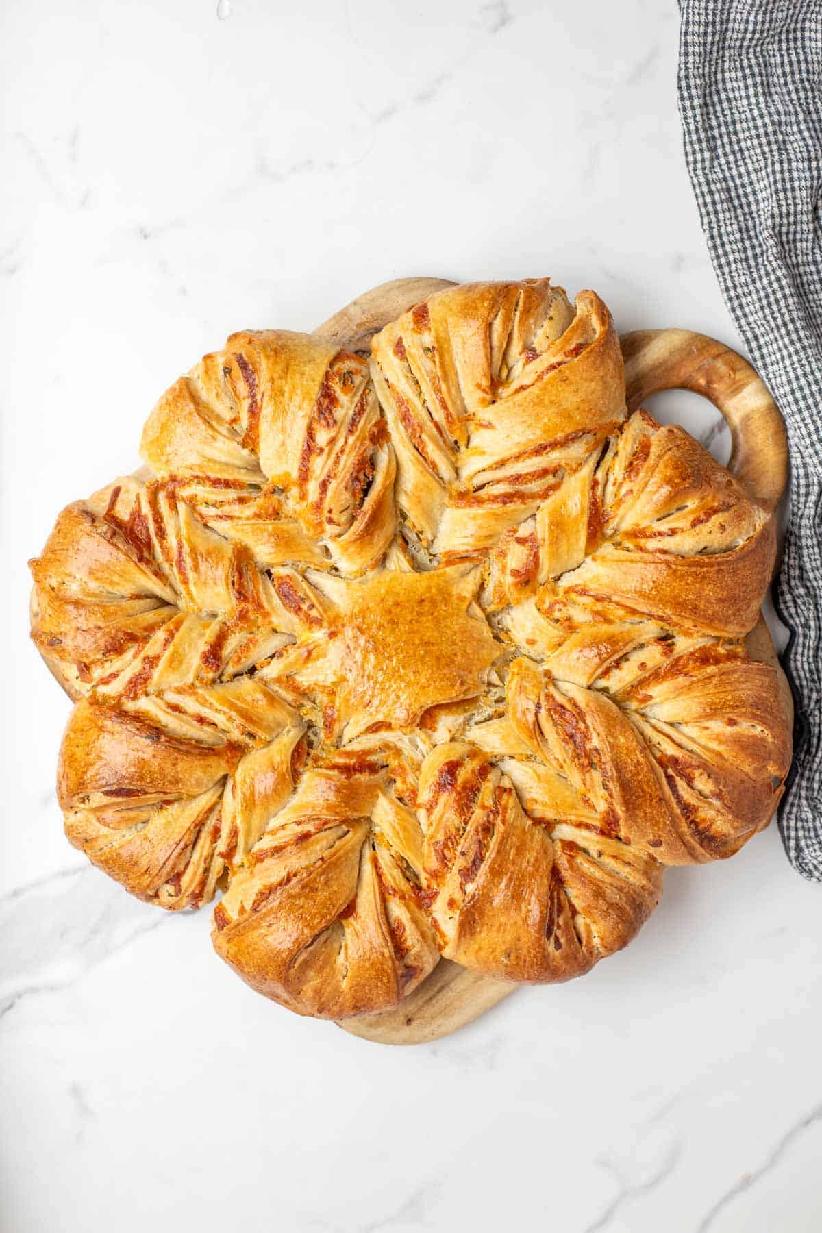 Fully baked sourdough cheese star on white marble countertop.