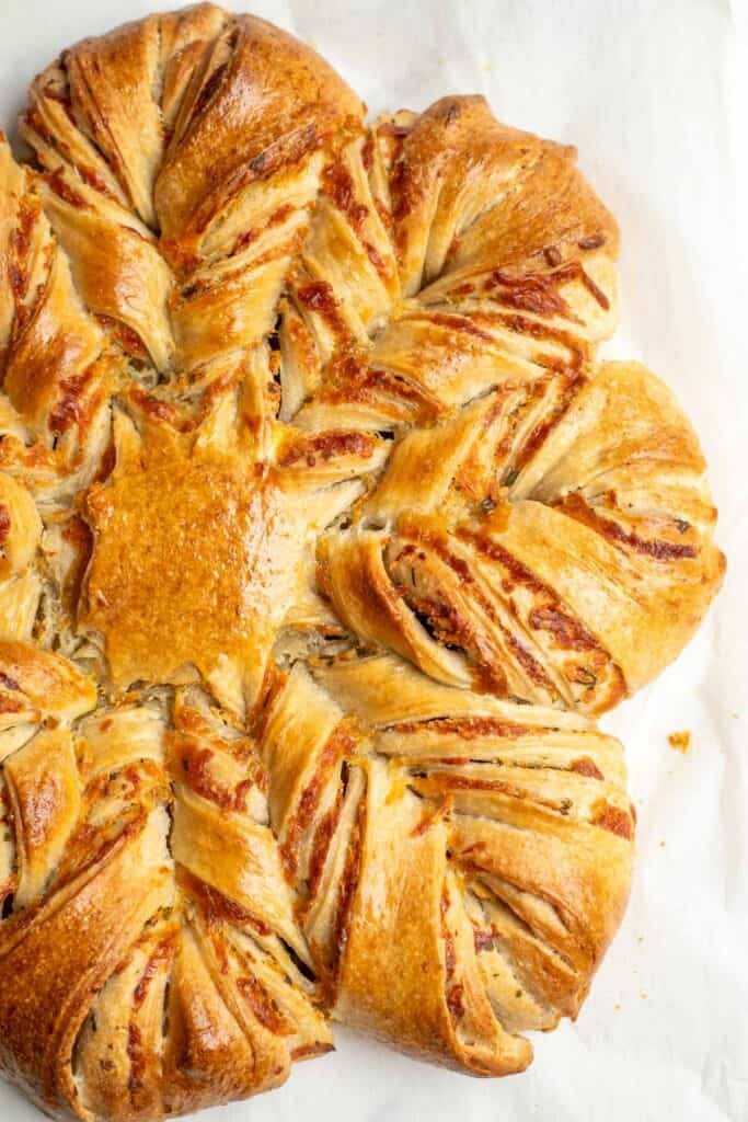 A freshly baked sourdough cheese star on white parchment paper.