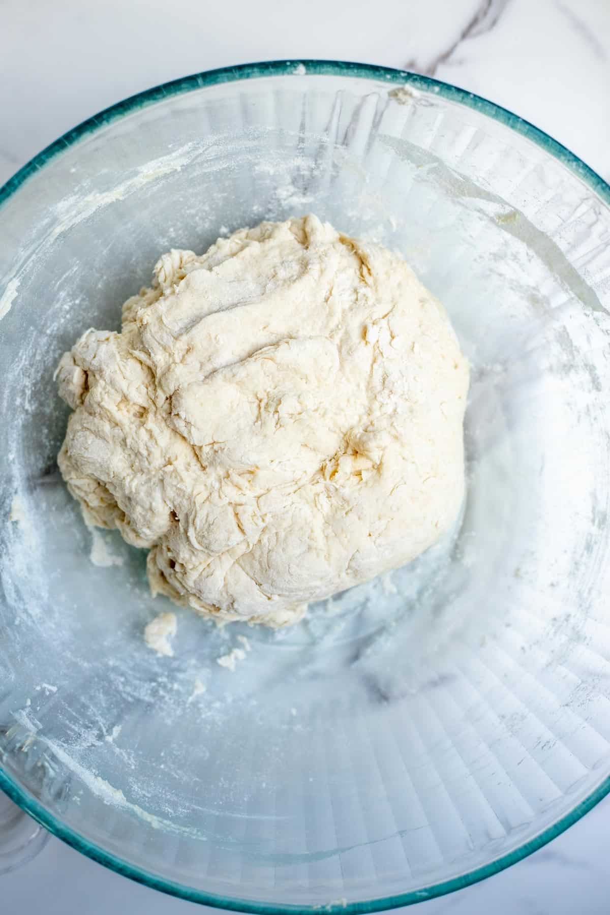 Water, sourdough starter, flour, and salt mixed together in a glass bowl.