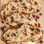 a wooden cutting board with three slices of chocolate cherry sourdough bread.