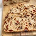 a chocolate cherry sourdough loaf of bread on a cutting board sliced in half.