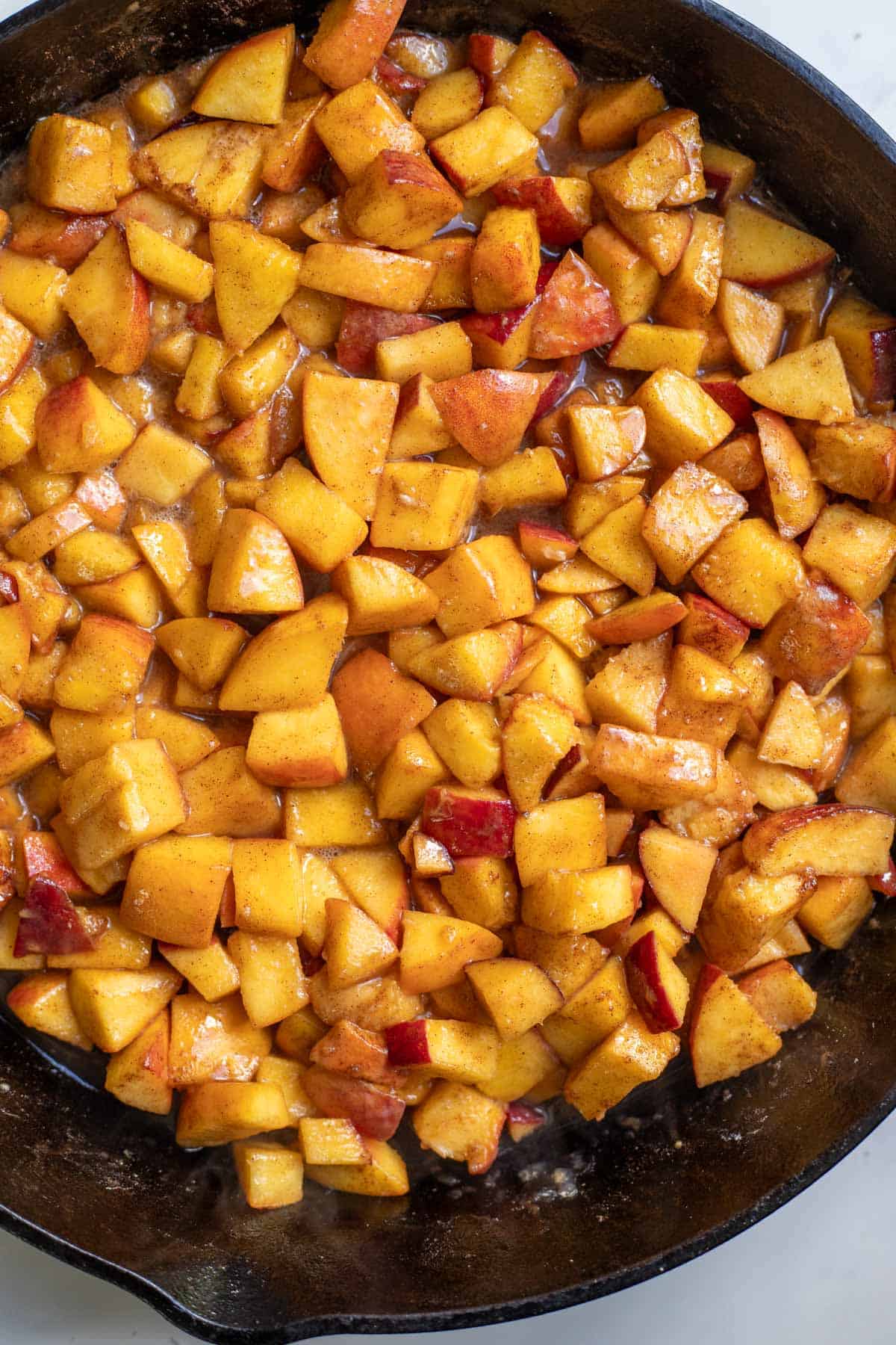 Cooked peaches in a cast iron skillet.