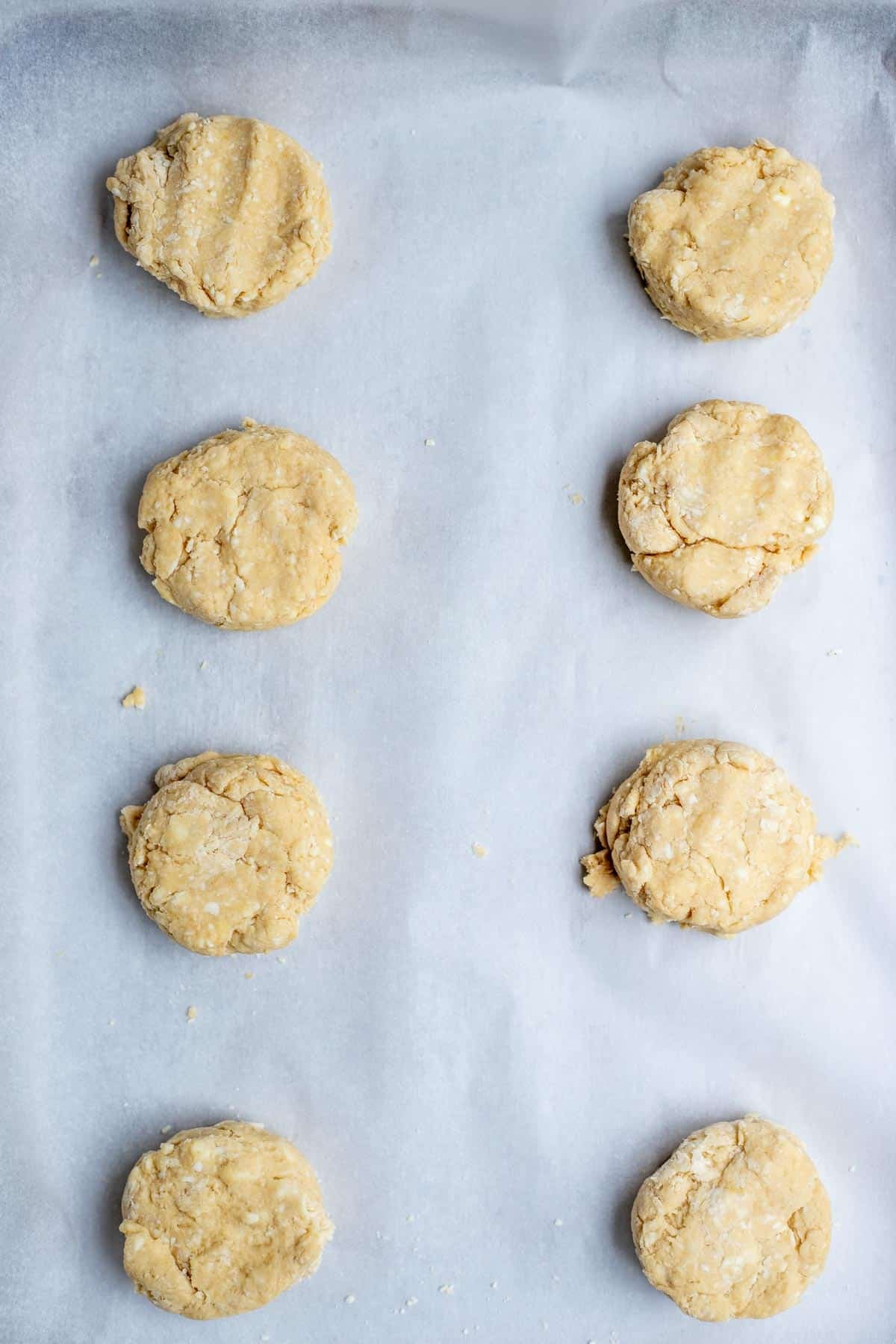 Sourdough sweet biscuit dough scooped out onto a parchment lined baking sheet.