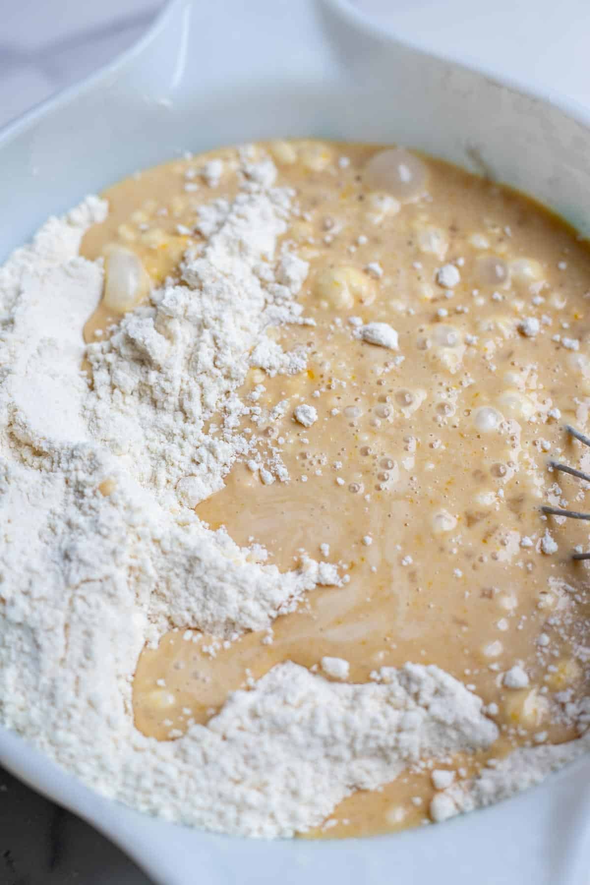Dry ingredients mixed with wet ingredients in a white mixing bowl.