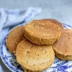 five whole wheat crumpets on a blue decorative plate.