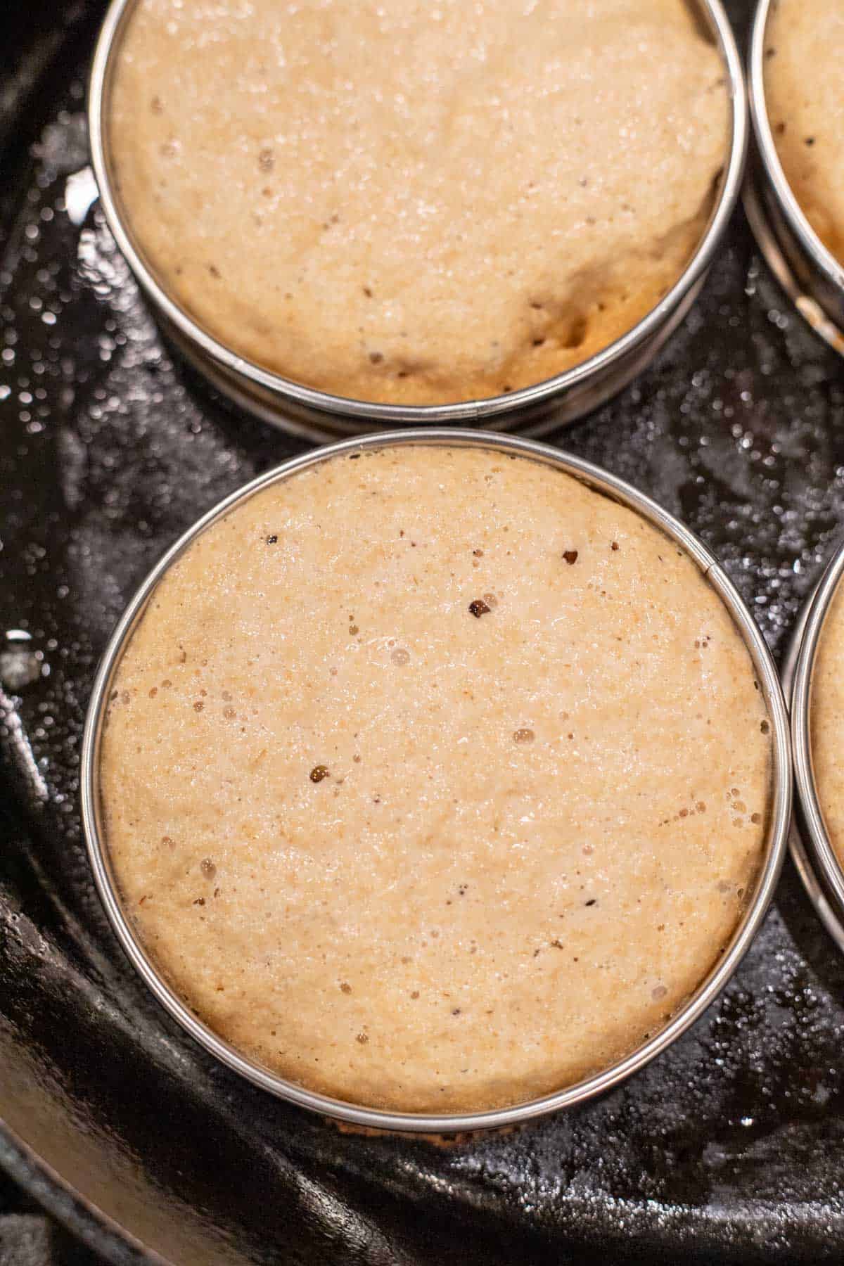 Freshly baked crumpets inside of a ring mold.