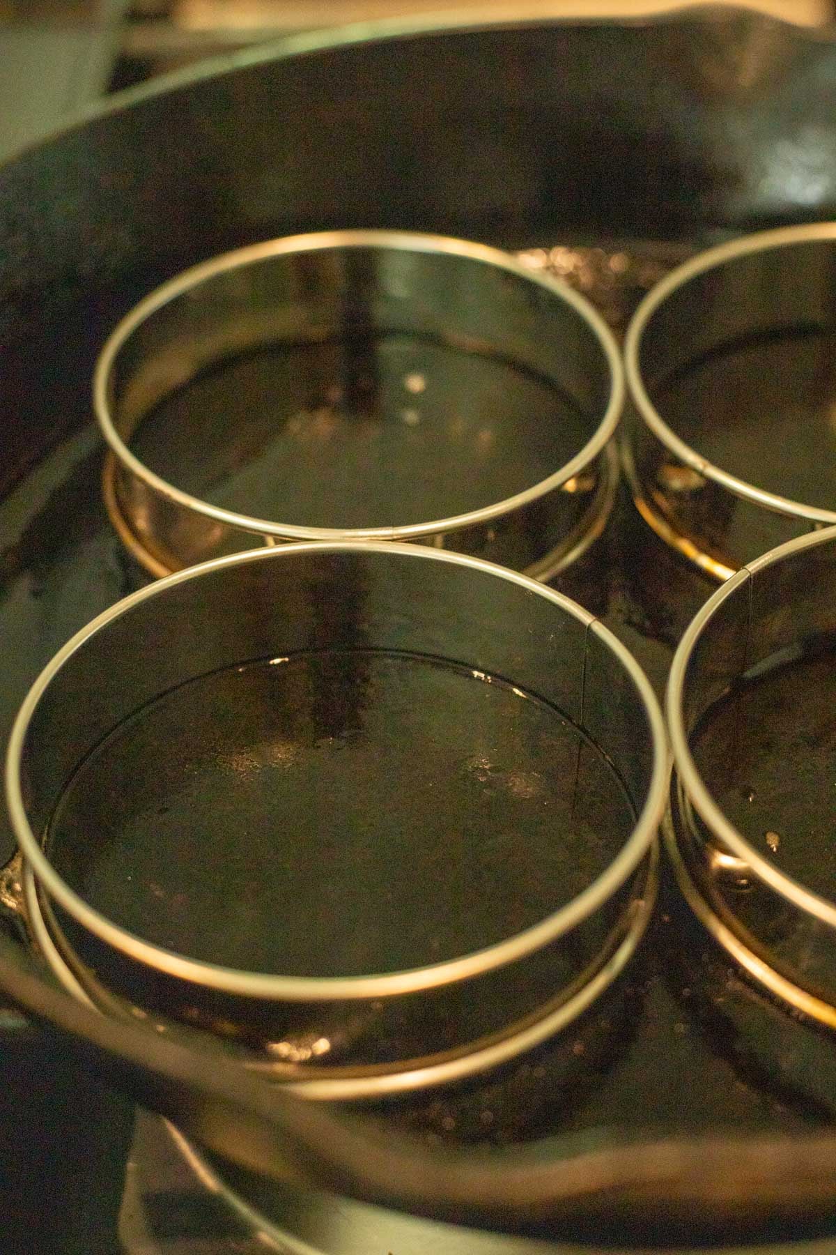 Greased crumpet rings on a baking sheet.