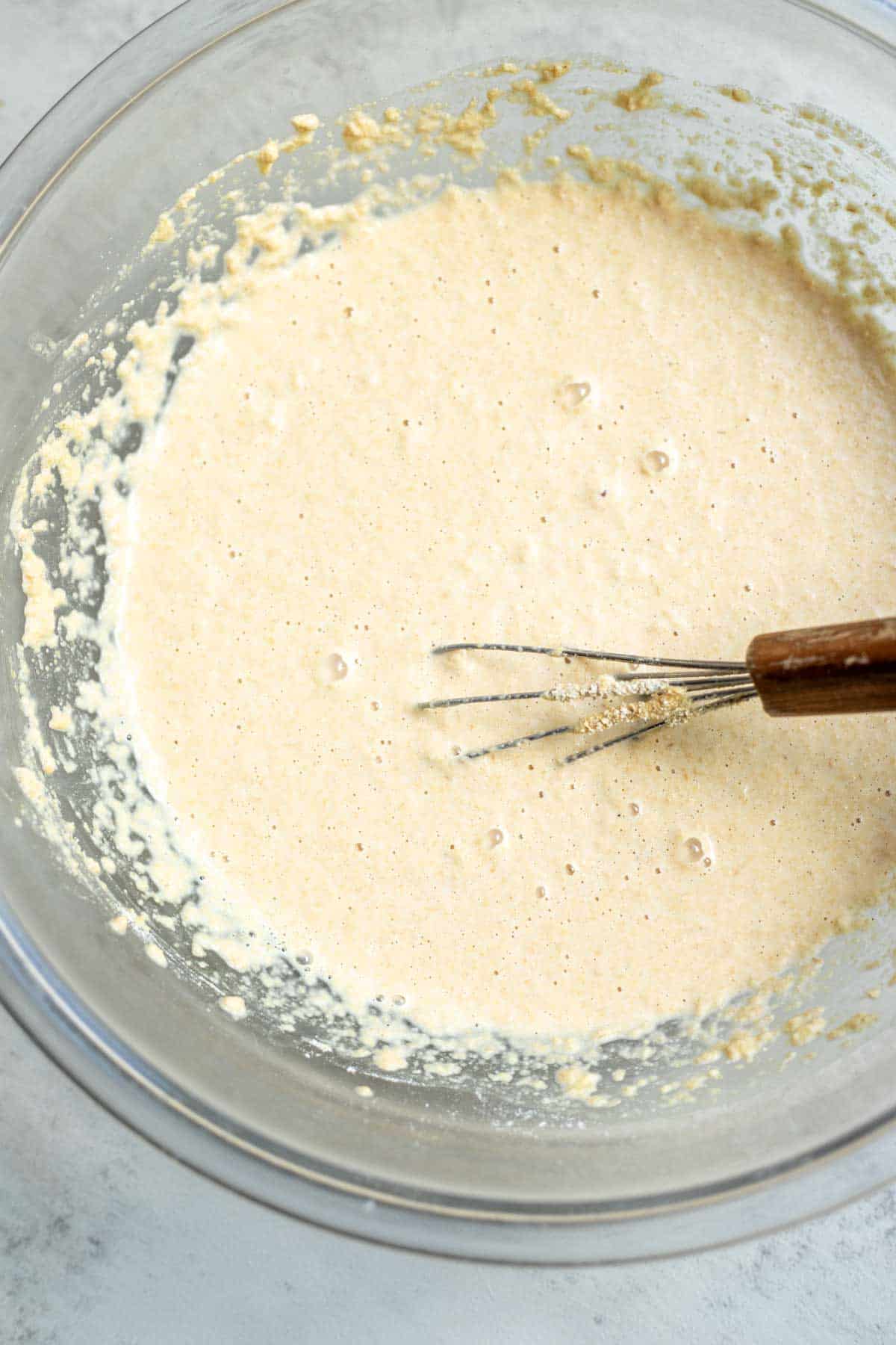 Flour, yeast, water, baking soda, sugar, and salt whisked together in a glass mixing bowl.