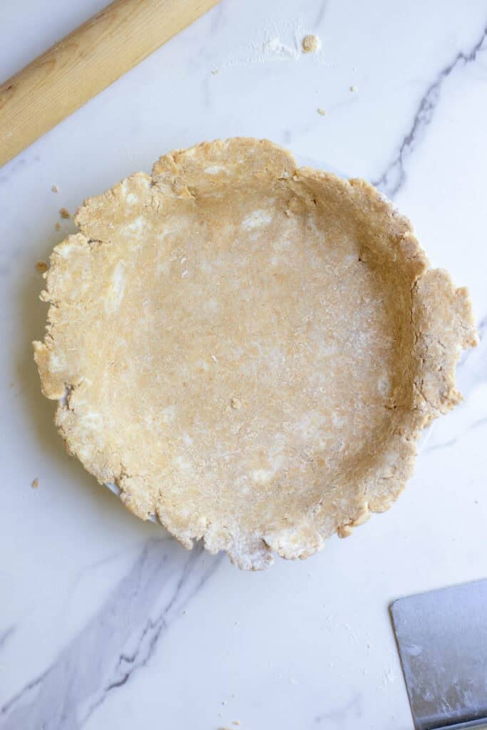 A pie crust rolled out and placed on top of a pie pan sitting on a countertop.