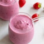 Two small glass cups with glass straws full of kefir smoothie.