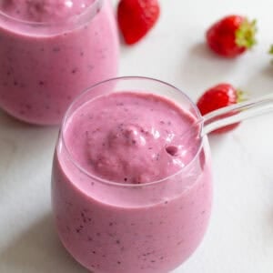 Two small glass cups with glass straws full of kefir smoothie.