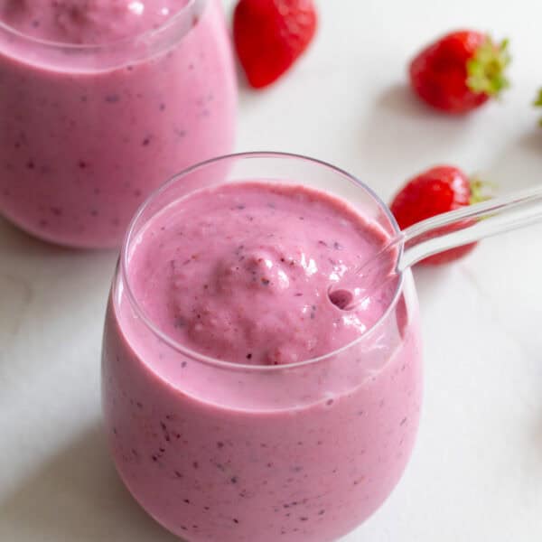 Two small glass cups with glass straws full of kefir smoothie.