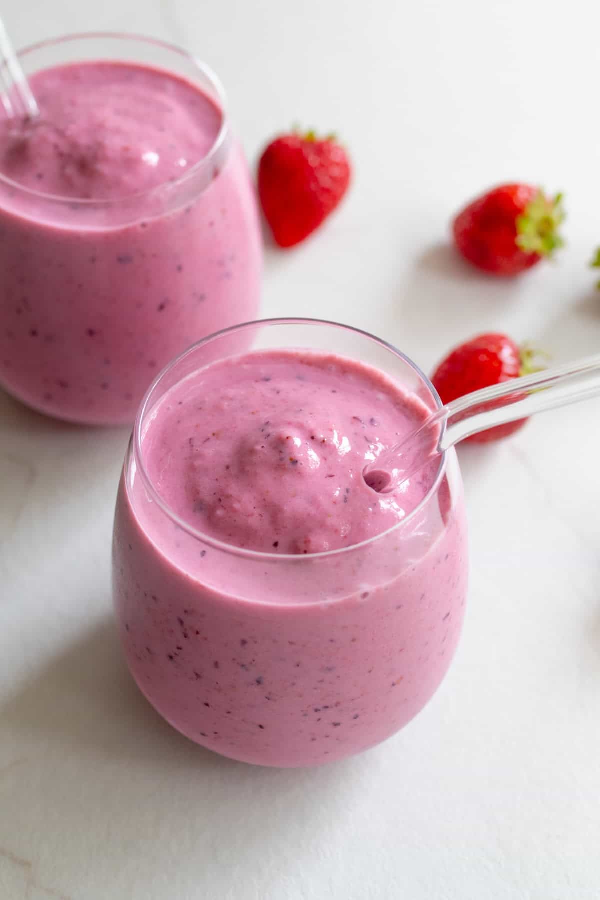Two small glass cups with glass straws full of kefir smoothie.