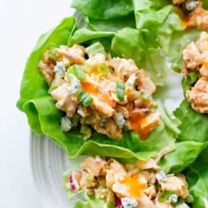 Lettuce cups with buffalo chicken salad in them on a serving platter.